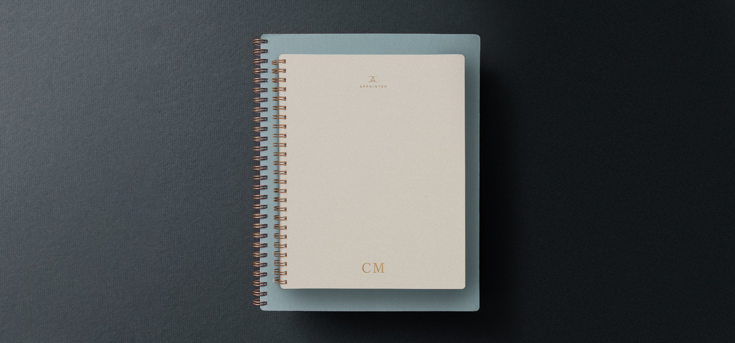 A 2022 planner sits atop a gray gift box agains a dark gray gradient background
